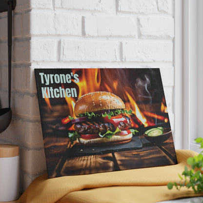 Personalized glass cutting board featuring a flame-grilled burger design on a rustic wood background with a custom name displayed on a kitchen counter.